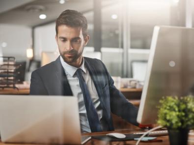 A person in a suit and tie looking at a computer